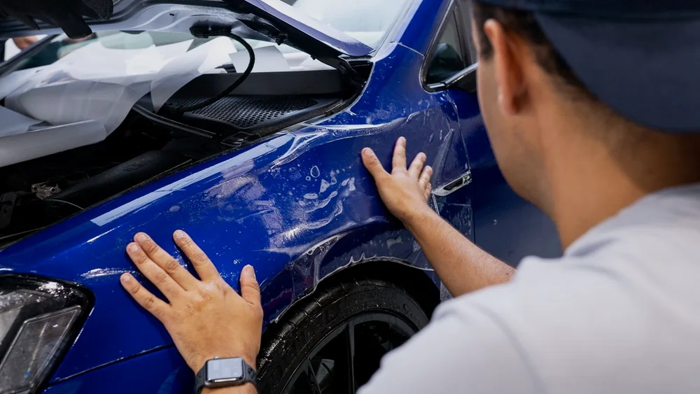 Need for Studio installing paint protection film on the front guard of a blue car