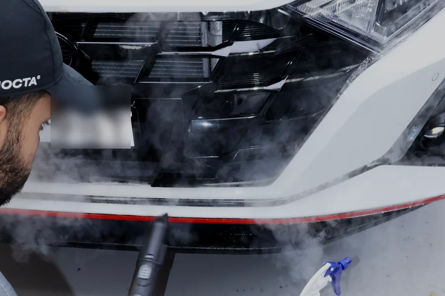 Front bumper of a white car being prepared during a paint protection film installation