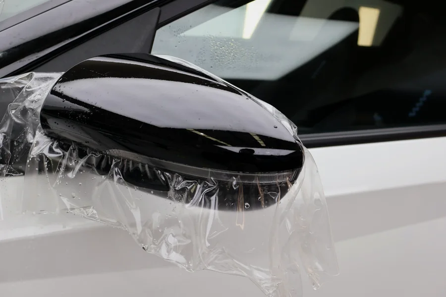 Paint protection film being applied to a black mirror cap