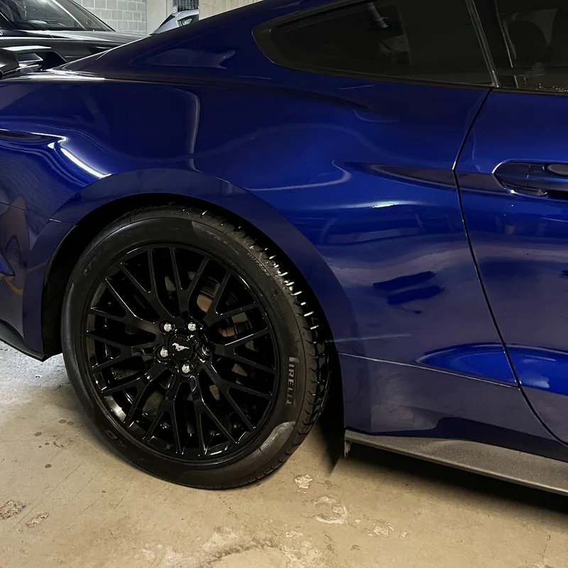 Deep blue paintwork and wheel of a sports coupe after a maintenance wash
