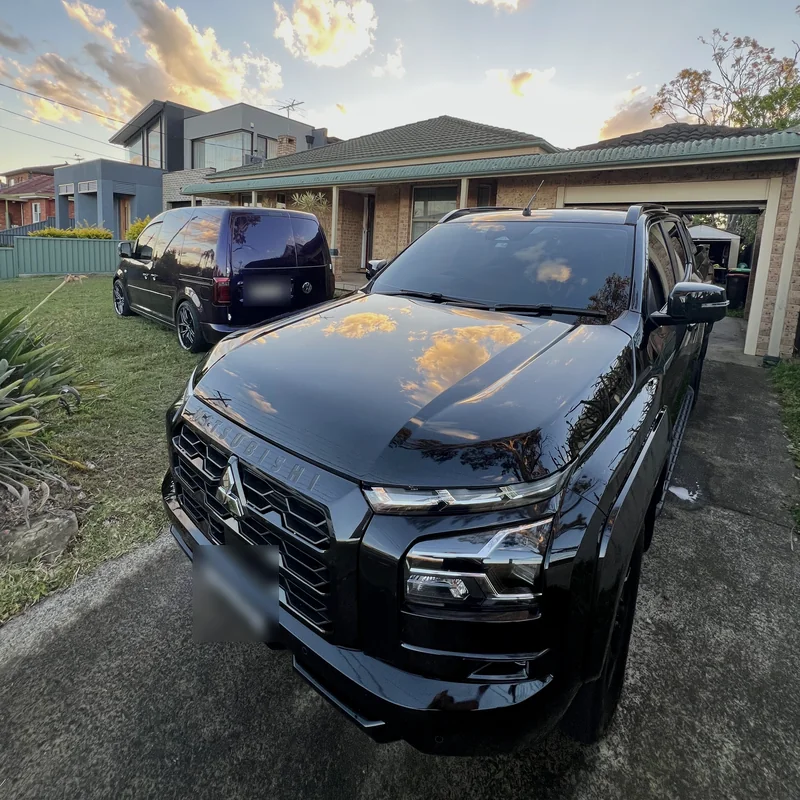 Black dual-cab ute washed in a customer's driveway with the Need for Studio van parked behind it